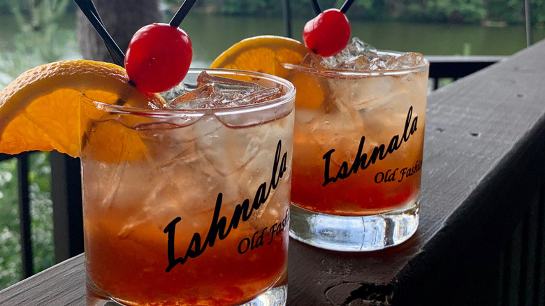 Two Wisconsin old fashioned cocktails sitting on a deck railing