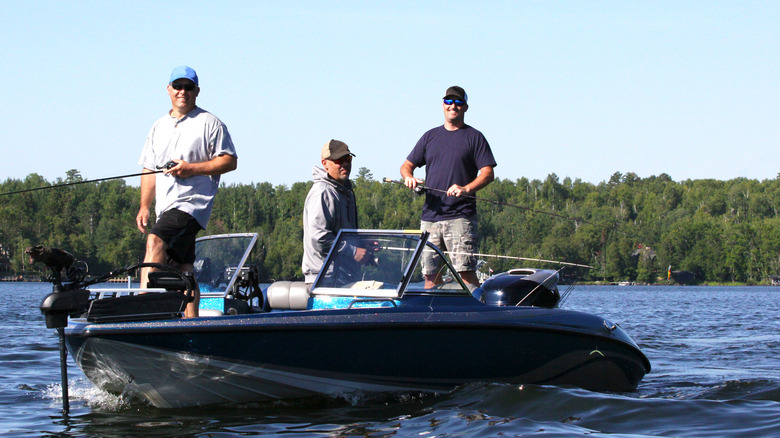 Three men stand on a fishing boat in a lake