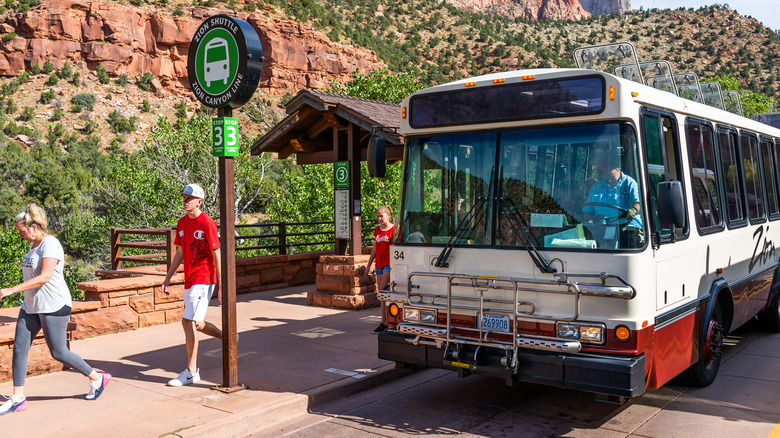 Zion National Park cliffs at shuttle bus in summer with people waiting to board in Utah at visitor center stop 3