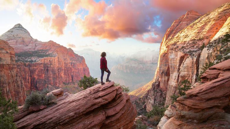 A woman standing on a rock outcrop overlooking Zion Canyon in Zion National Park