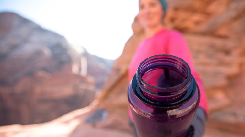 A female hiker holks a purple Nalgene water bottle