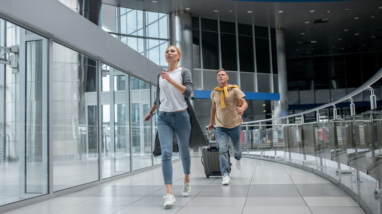 Two people running through airport