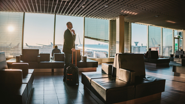 Man in suit stands in airport lounge