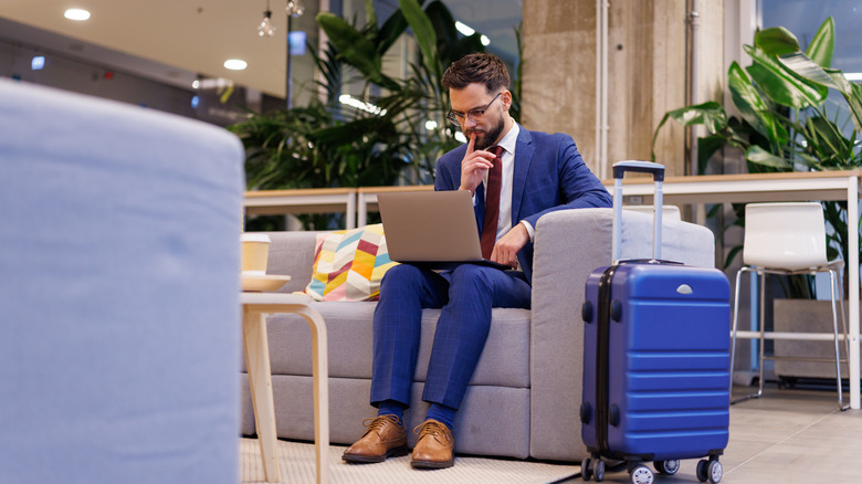 Man in suit has laptop open in lounge
