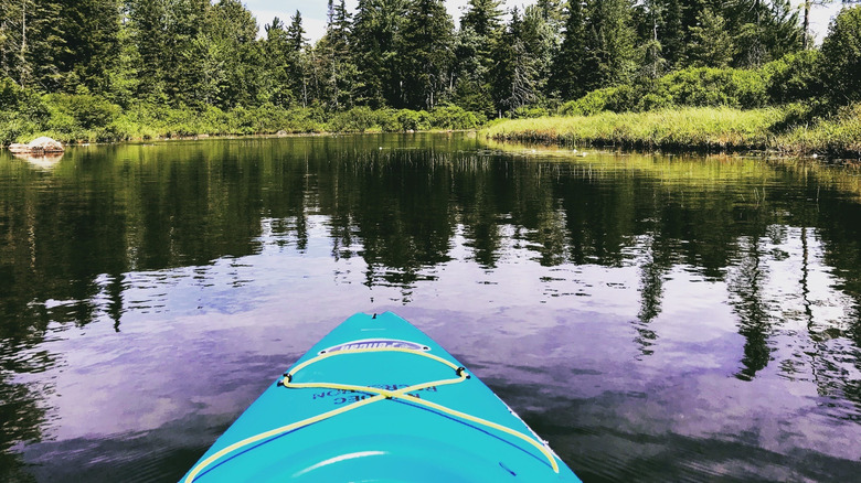 Kayaker paddles across calm Nicks Lake in Old Forge, New York