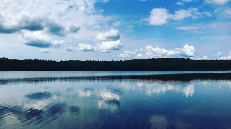 Clouds float in blue sky over rippling water at Nicks Lake in Old Forge, New York