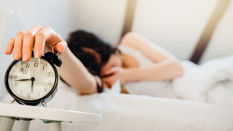 Woman turning off alarm clock