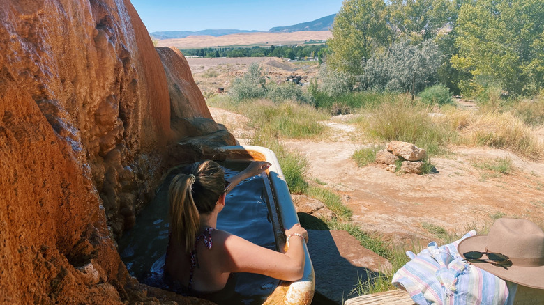 A woman relaxing while looking at the view in a tub at Mystic Hot Springs in Utah