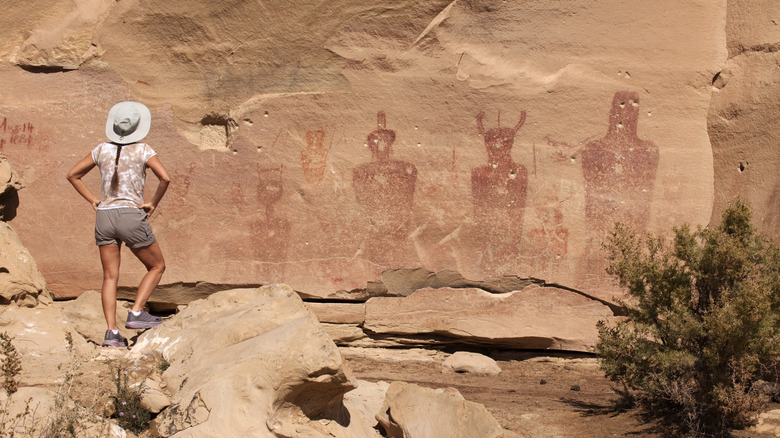 Woman looking at Indigenous rock art on the walls of Sego Canyon in Utah