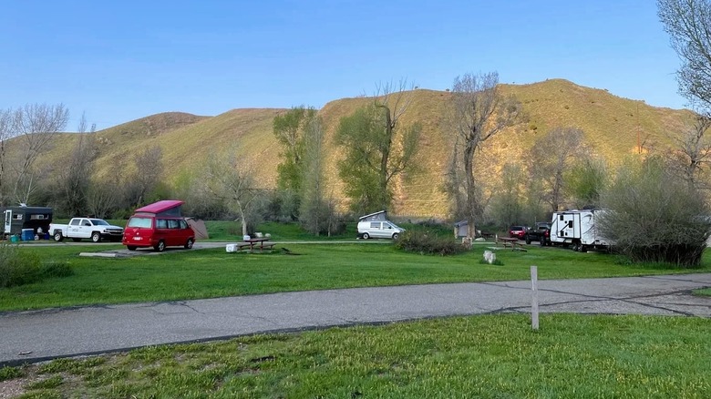 Views of a campsite at Rockport State Park in Utah, with several campers, and surrounded by greenery and hills.