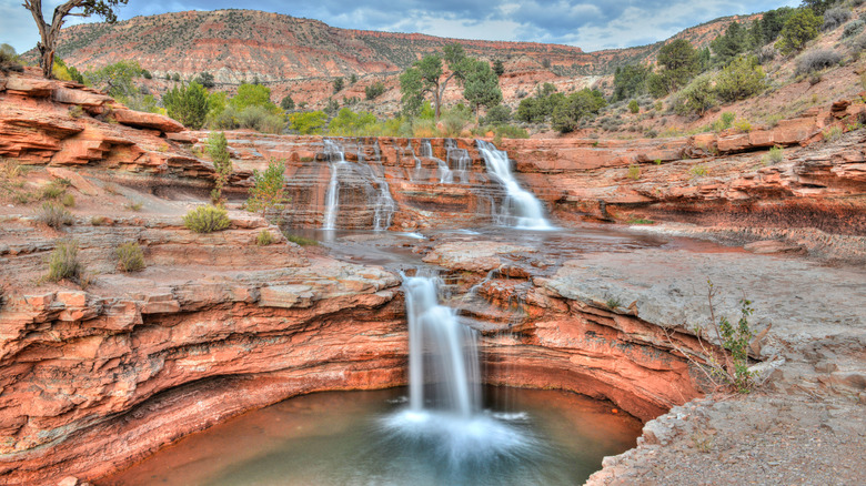 Three cascades over red rocks at Toquerville Falls, Utah.