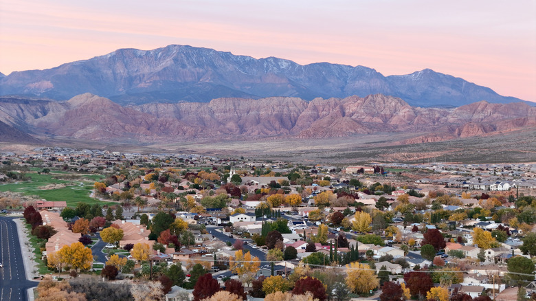 Aerial views of Washington City, Utah surrounded by sparse foliage, with red cliffs and mountains in the backdrop