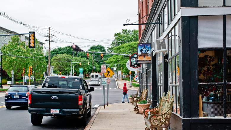Shops and trees lining a main road in downtown Uxbridge, Massachusetts, as cars travel down the road