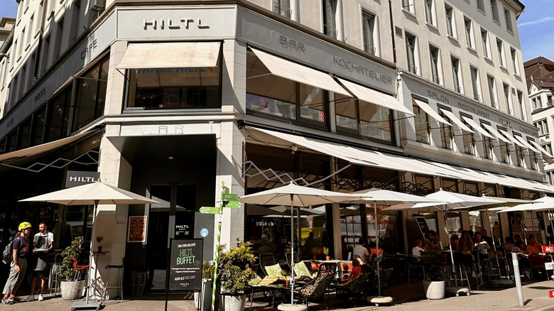 The facade of Hiltl with umbrellas and outdoor seating, the world's oldest vegetarian restaurant.