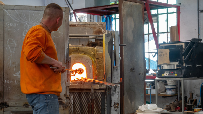 A glassblower shapes a glass piece in a traditional glass studio on Murano Island, Venice,