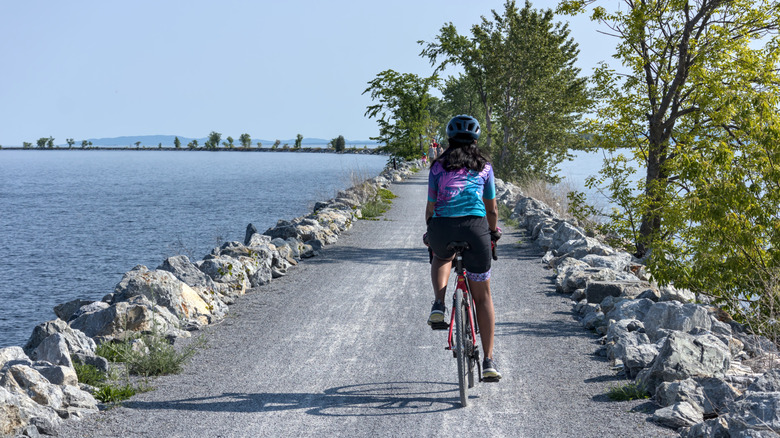 A ﻿﻿woman rides a bicycle on the gravel cycling path in Burlington, Vermont
