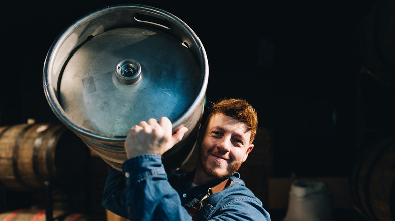 A man carrying a beer barrel on his shoulder at a microbrewery