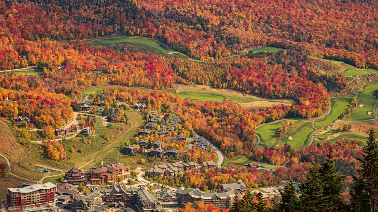Green of Stowe Mountain Resort's golf course contrasted with the reds and oranges of the surrounding fall foliage