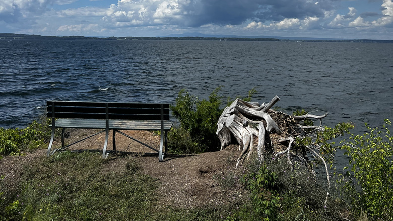 Scenic view of a wooden bench on Burton Island facing Lake Champlain under a dramatic cloudy sky.