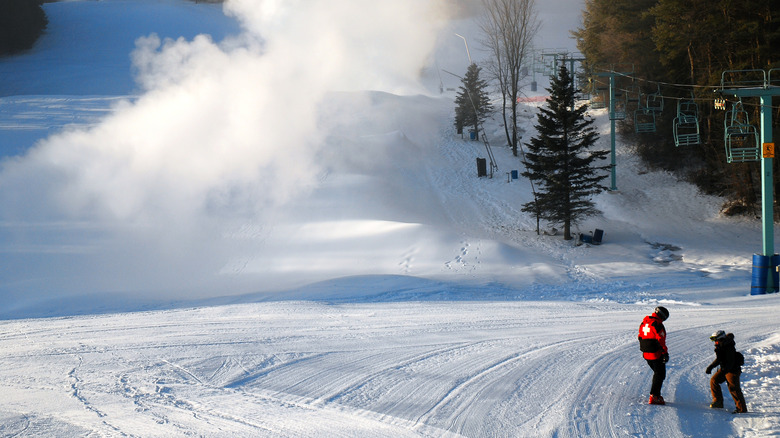 A ski patroller and child meet on a freshly groomed trail in the Saskadena Six Ski Area, Vermont