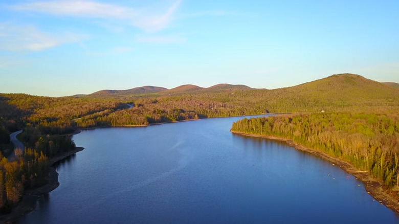 Forested hills and large lake bathed in golden hues at Molly's Falls Pond State Park