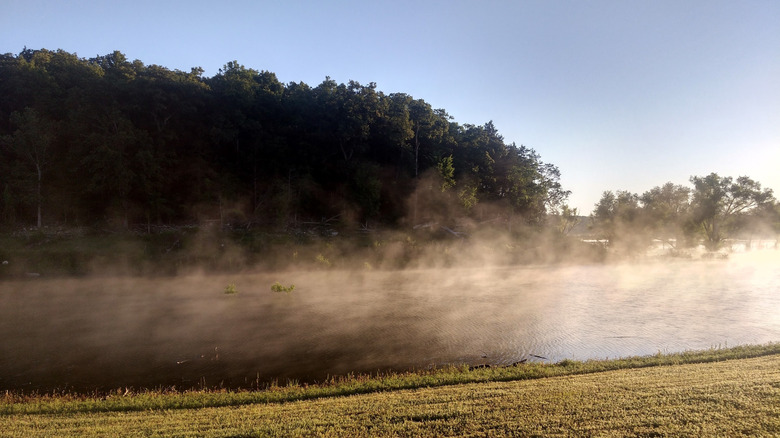 mist rising off of a lake with trees in the background at Beaver Creek Park, Missouri