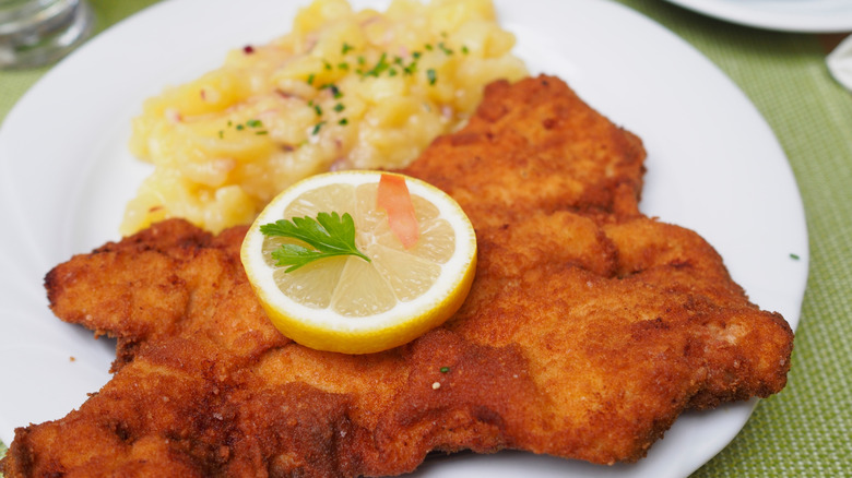Schnitzel on a plate with lemon and potato salad
