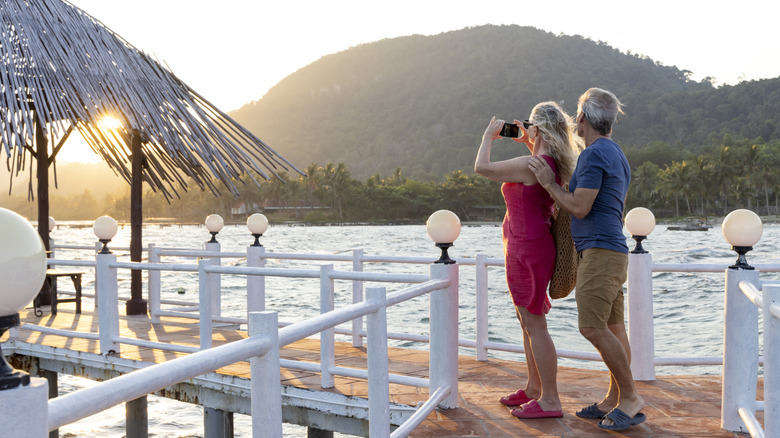 A mature couple on a wood deck overlooking the sea and mountains on Phu Quoc island, Vietnam