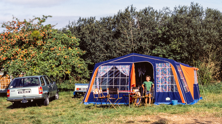 A family campsite with a tent and car parked nearby in the 1980s