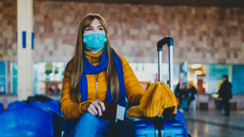 woman in mask waits for flight