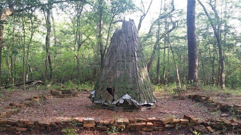 Steeple of the Wash Woods Methodist Church, a conical structure of moss-covered shingles surrounded by a low brick wall with trees in the background