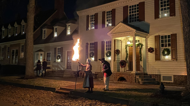 Person lights a cresset during Grand Illumination in Colonial Williamsburg