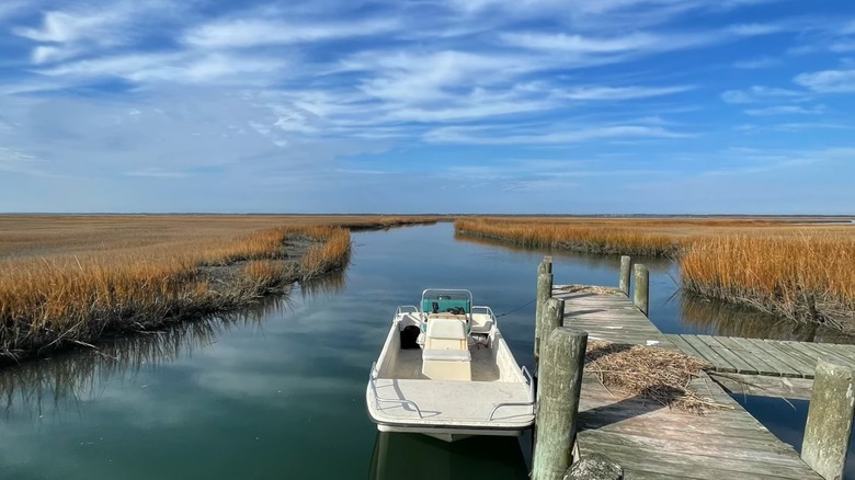 A small white boat docked on a waterway among marshes on Parramore Island, Virginia