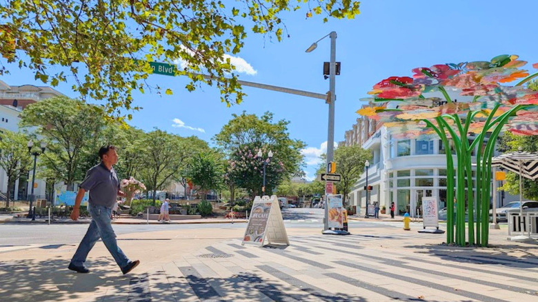 Man walking across the street at The Crossing Clarendon in Arlington, VA on a sunny day