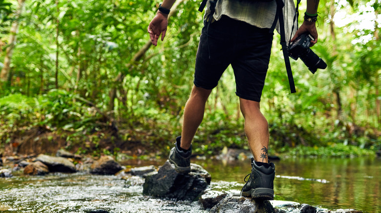 Hikers attempting shallow river crossing.