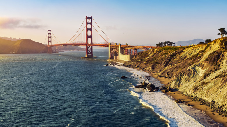 The Golden Gate Bridge in San Francisco with waves crashing ton shore during golden hour.