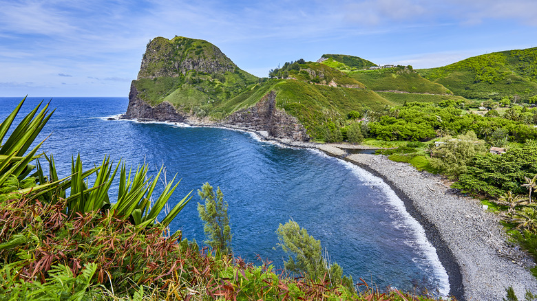 A white sand beach with green hills on the coast of the island of Maui