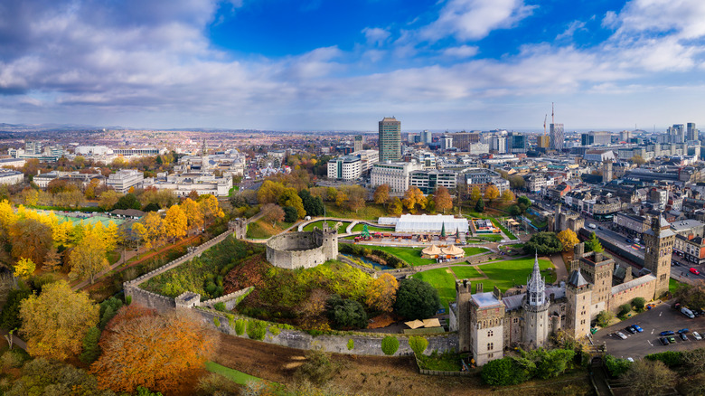 A drone view of Cardiff, Wales, with Cardiff Castle and parklands in the foreground and city buildings in the background