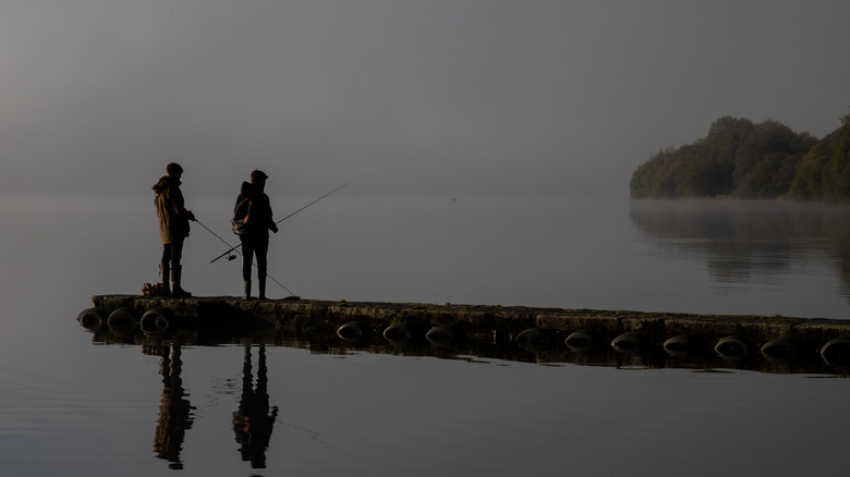 Two people fishing in the mist along the shoes of Llyn Tegid