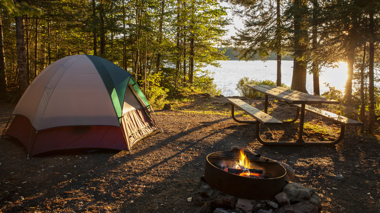 Tent at a campsite with a picnic bench and lit fire pit