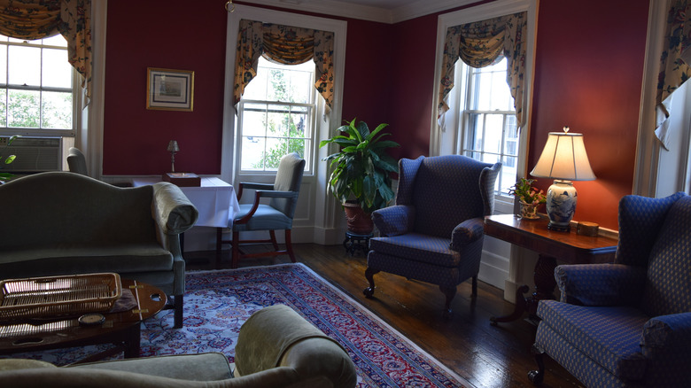 red walls in a living room with blue chairs and windows