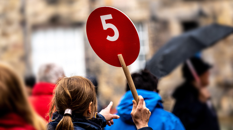 A tour guide holding a red circular sign for a tour group to follow
