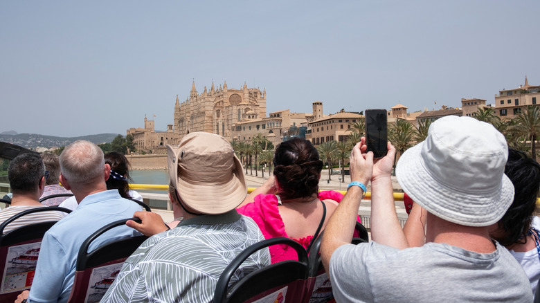 Tourists taking photos from an open-air tour bus