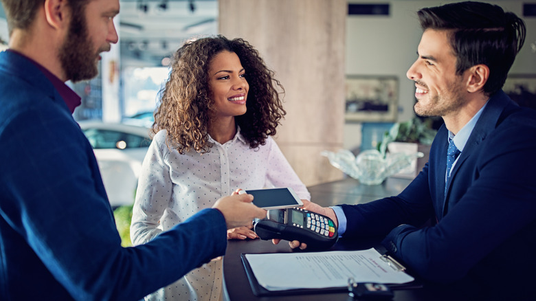 Couple at rental car counter paying with credit card