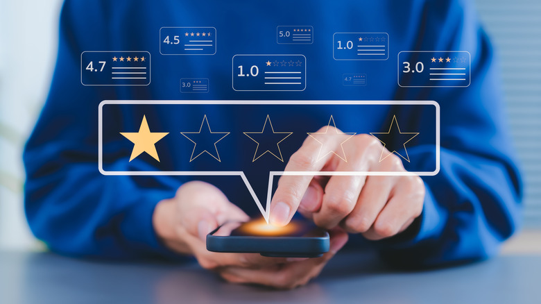 Image of person pointing to their phone with graphics of reviews, including a one-star review
