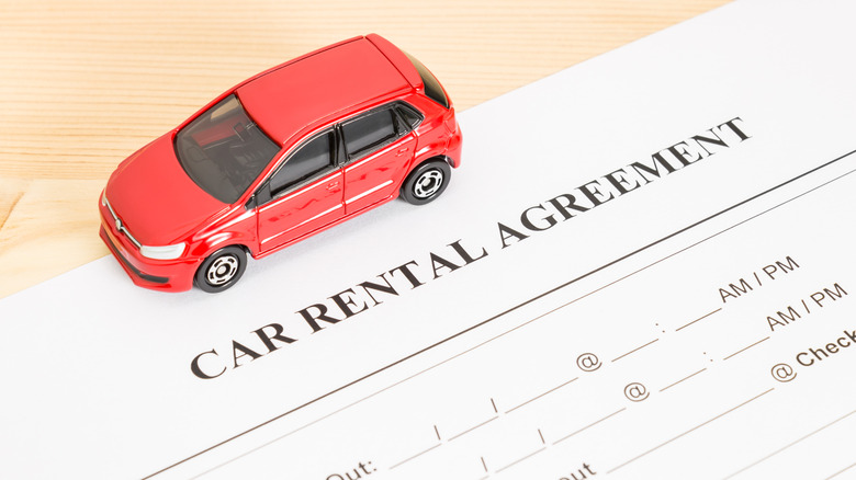 Miniature car on top of car rental agreement