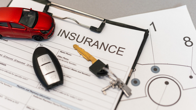Car insurance contract with keys, key fob, and mini car sitting on top