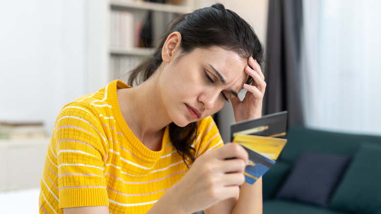 Woman holding her forehead with credit cards in her hand