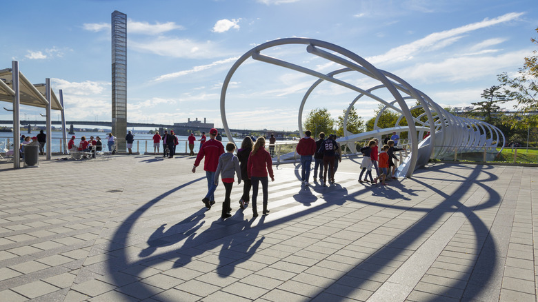 Visitors walking and standing along the waterfront at Yards Park in Washington, D.C., featuring a modern cylinder-style bridge
