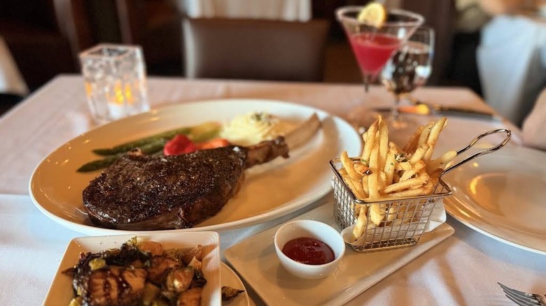 A plate of steak, fries, and sides on a white-clothed table at Sovereign Steakhouse